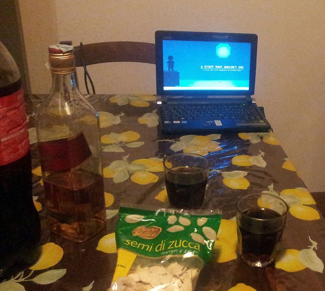 Photo of kitchen table with drinks and laptop with loaded screenshot of released game.